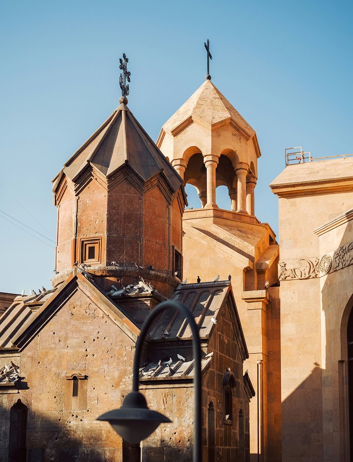 Ancient stone church with crosses on rooftops under clear sky in one of the oldest countries in the world.