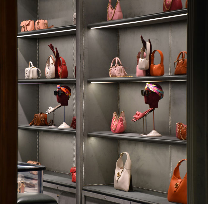 Luxury boutique display of designer handbags and mannequin heads, Greedy Mom theme suggested by opulent purse collection Luxury boutique display of designer handbags and mannequin heads, Greedy Mom theme suggested by opulent purse collection