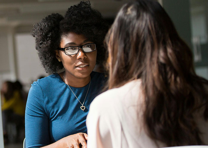 Two women having a serious conversation indoors, representing neurodivergent people discussing habits thought to be normal.