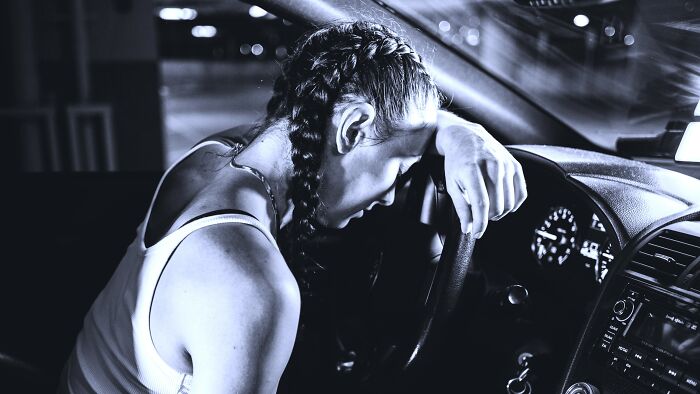 Woman resting her head on the steering wheel inside a car, illustrating people who did the right thing debate.