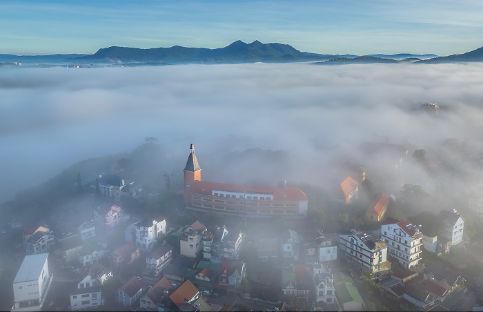 Aerial view of an ancient town surrounded by fog with mountains in the background, representing oldest countries.