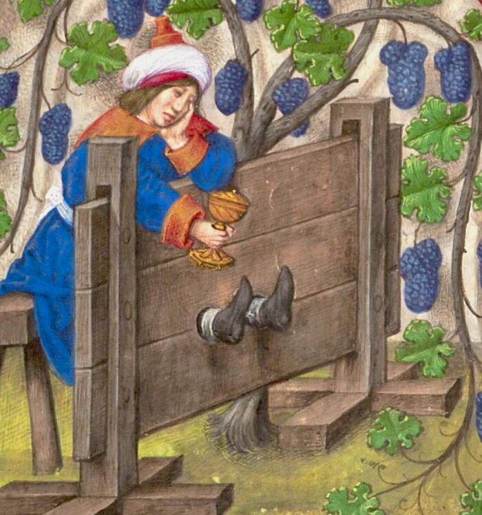 Medieval painting of a person stuck in wooden stocks holding a goblet under grapevines, perfect for meme captions and punchlines.