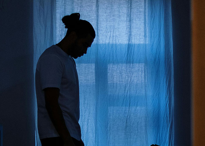 Silhouetted person inside dimly lit room with blue curtains, illustrating kids with no filter revealing family lore.