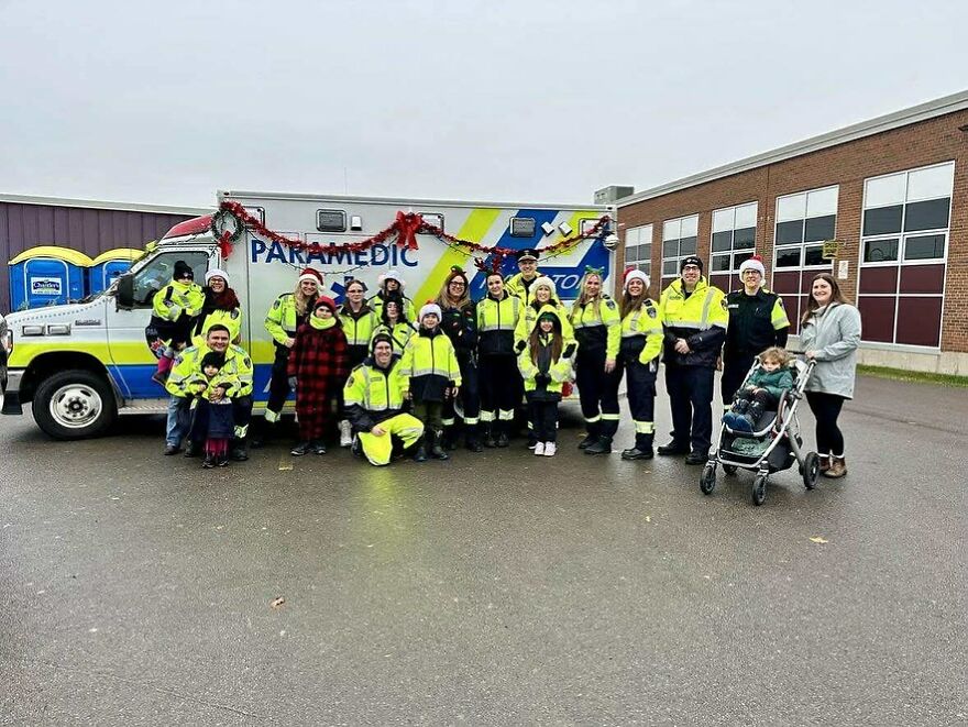 Group of paramedics in high-visibility uniforms standing in front of an ambulance, illustrating work-life balance challenges.