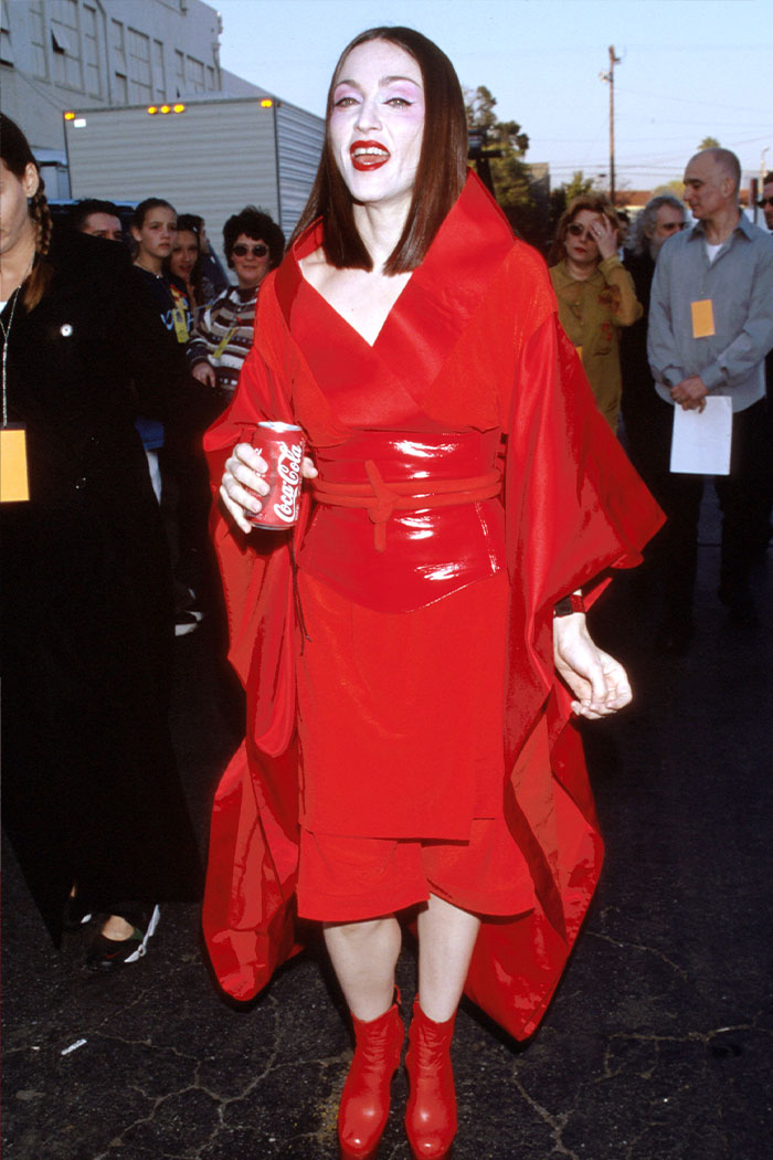 Woman in a bold red outfit and matching boots at a wild Grammys look event holding a can of Coca-Cola.