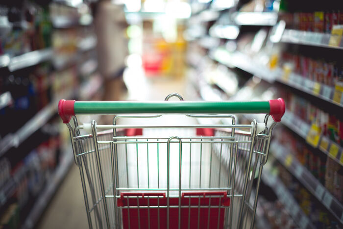 Empty shopping cart in an aisle of a grocery store illustrating weird and satisfying situations where people said not my problem anymore.