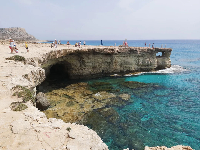 Most Stressful Countries: tourists on sunlit limestone cliffs above turquoise sea and coastal caves