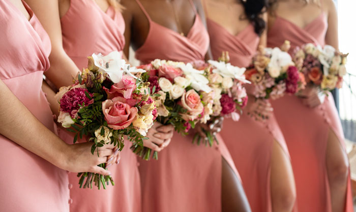 Bridesmaids in matching pink dresses holding floral bouquets before a wedding with a bridezilla moment approaching. Bridesmaids in matching pink dresses holding floral bouquets before a wedding with a bridezilla moment approaching.