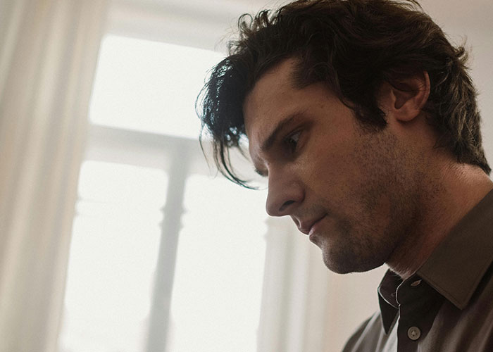 A thoughtful man indoors reflecting on life changes after discovering he is not the biological parent.