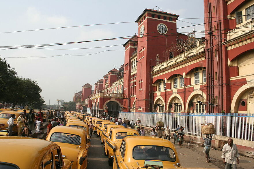 Yellow taxis lined up in heavy traffic outside a historic red building in a city known for worst traffic congestion.