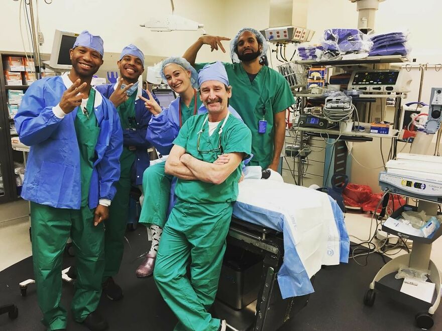 Group of medical professionals in scrubs smiling and posing in a busy operating room showcasing work-life balance challenges