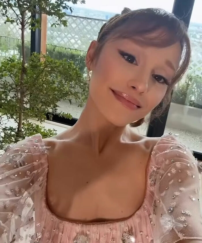 Ariana Grande posing in a pink embellished dress with makeup, involved in a red carpet controversy with Leighton Meester.