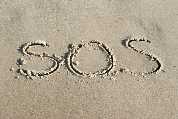 SOS escrito na areia de uma praia, simbolizando o código simples usado em missões de resgate em todo o mundo para emergências. SOS escrito na areia de uma praia, simbolizando o código simples usado em missões de resgate em todo o mundo para emergências.