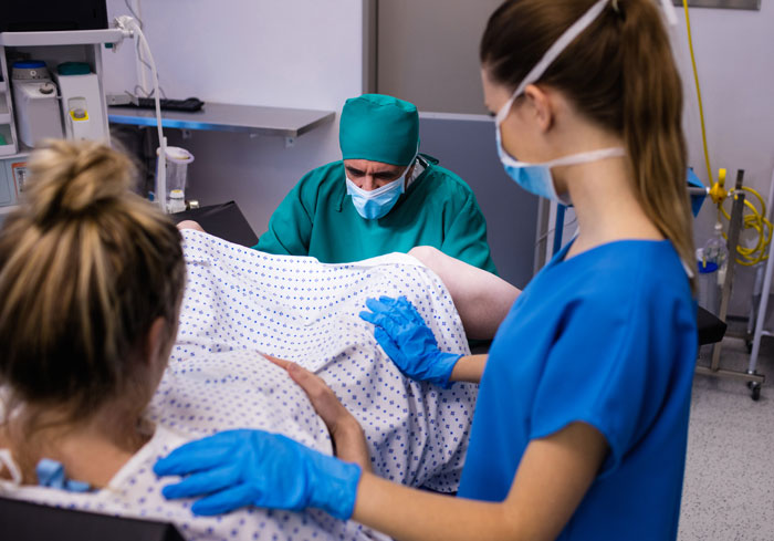 Pregnant woman in delivery room with medical staff, highlighting conflict over fianc&eacute;&rsquo;s mom presence during childbirth.