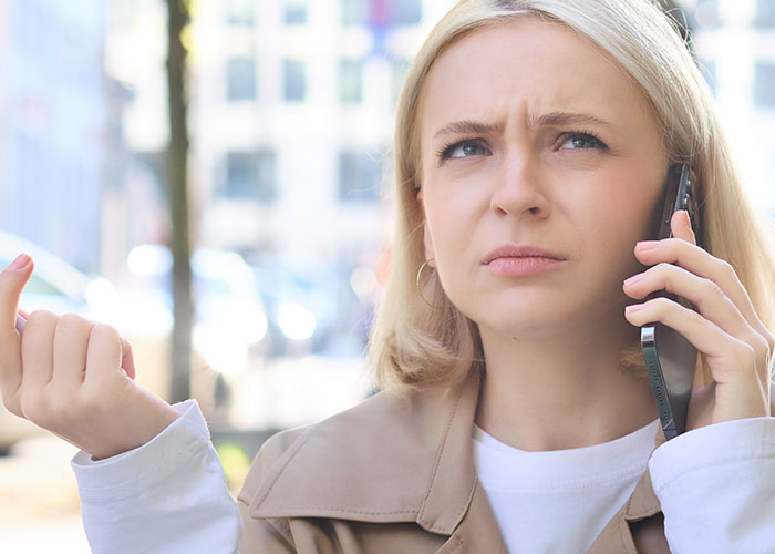 Woman with concerned expression on phone call outdoors, illustrating babysit ghosting and a call for help situation.