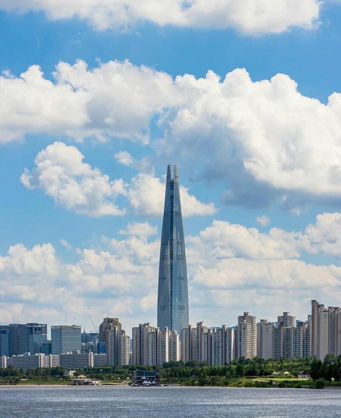 City skyline with a tall skyscraper under a cloudy sky, representing countries that sleep the most according to OECD data.