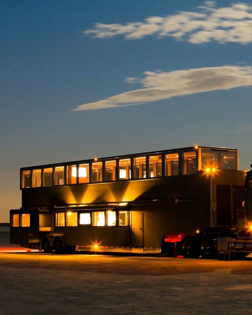 Luxury double-decker celebrity house on wheels illuminated at night, showcasing lifestyles of the ultra-rich.