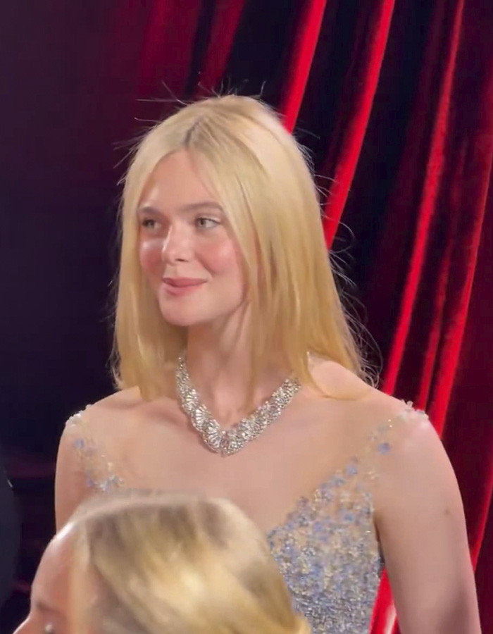 Elle Fanning at Golden Globes wearing a shimmering gown and necklace, showcasing her electric head look on the red carpet.
