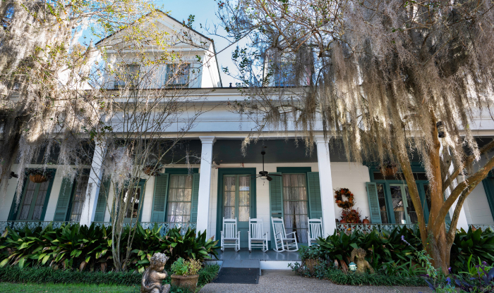 Historic southern plantation house with rocking chairs surrounded by moss-draped trees in a haunted place setting. Historic southern plantation house with rocking chairs surrounded by moss-draped trees in a haunted place setting.