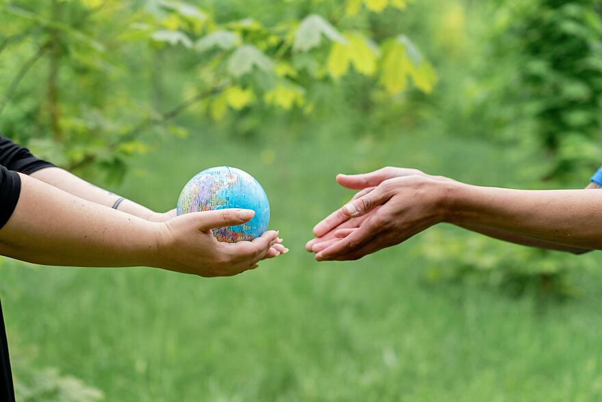 Person passing a small globe to another person, illustrating the concept of Earth cost and value. Person passing a small globe to another person, illustrating the concept of Earth cost and value.