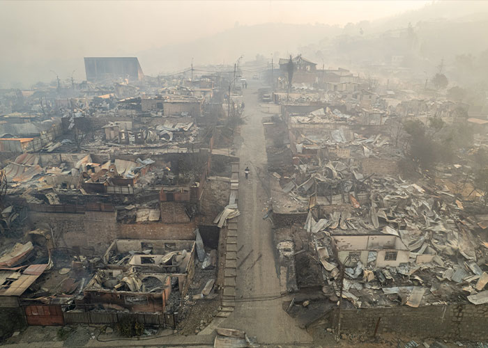 Aerial view of town destroyed by Chile wildfires, showing charred ruins and smoke-filled sky after overnight blaze.