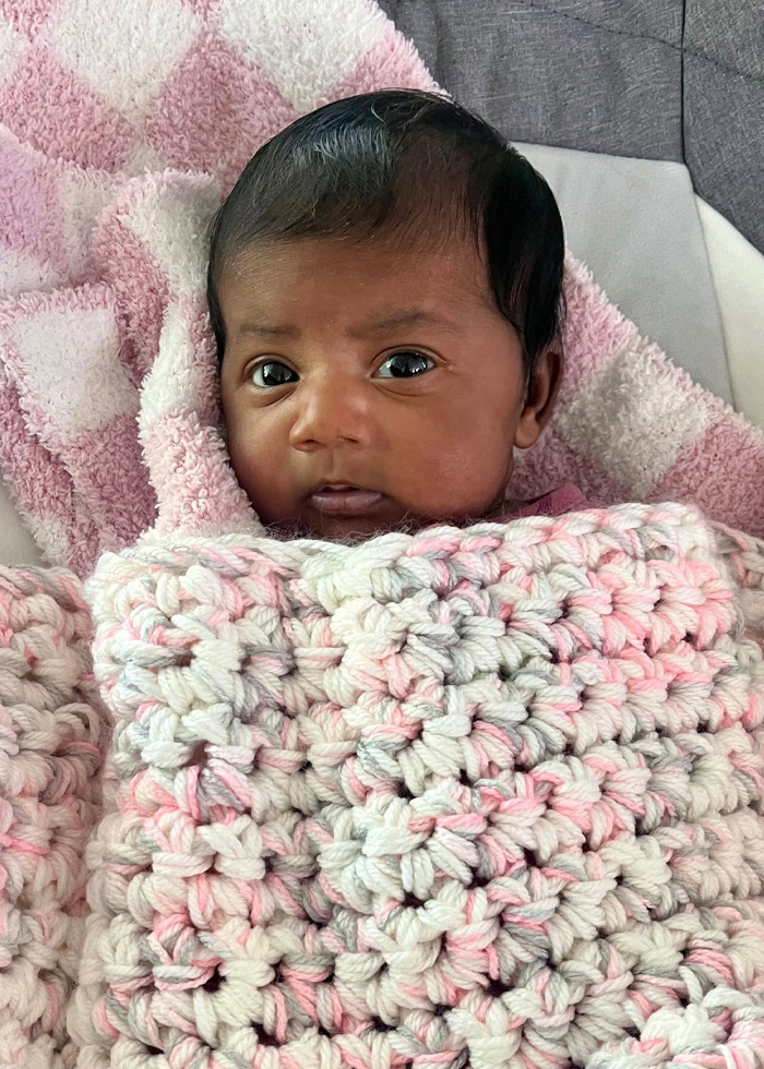 Newborn baby wrapped in pink and white blankets, representing a fertility clinic mix-up case involving parents and child delivery.