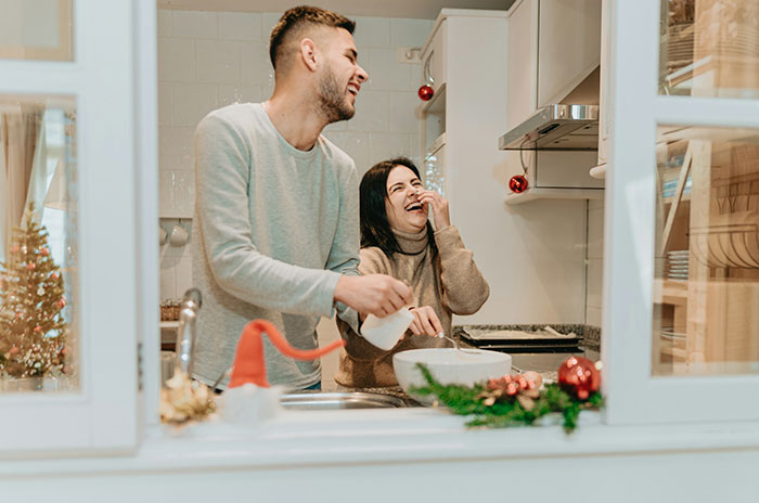 Couple laughing together in kitchen, highlighting karma and affair partner leaving after cheating on husband.