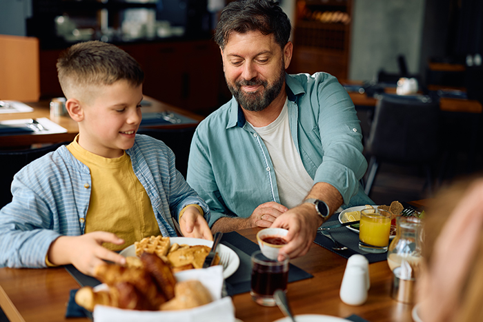 Dad and son celebrating at breakfast after conflict with a bully, showing bonding and praise for standing up. Dad and son celebrating at breakfast after conflict with a bully, showing bonding and praise for standing up.
