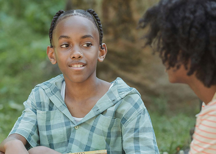 Two kids having a candid conversation outdoors, capturing the essence of kids with no filter sharing family lore.