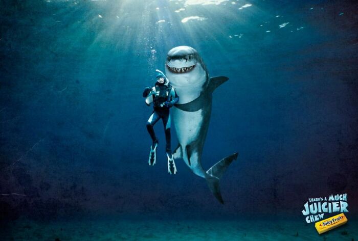 Underwater scene with a diver and a smiling shark, showcasing creative print advertisements using humor.