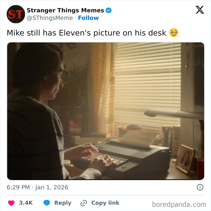Mike typing on a typewriter at his desk with Eleven's photo beside him, capturing a Stranger Things ending moment.