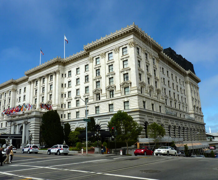 Historic luxury hotel exterior with flags, cars, and pedestrians on a clear day relating to Victoria body found story.