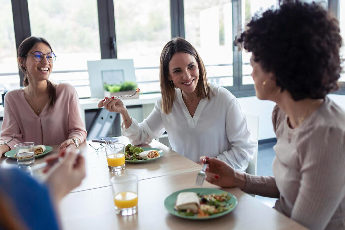 Colleagues enjoying lunch together in an office, highlighting bizarre office rules that frustrate employees.