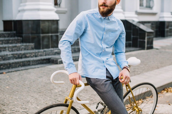 Man in a blue shirt sitting on a gold bicycle outdoors illustrating bizarre office rules that frustrate employees.