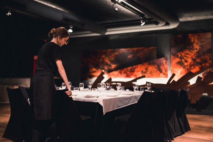 Waitress setting table in a restaurant with dim lighting, illustrating weird and shocking things people did in public with zero shame.