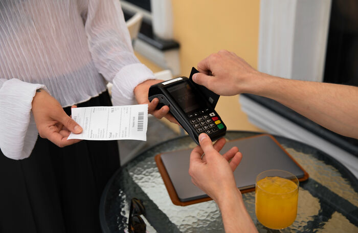 Customer using card payment at a restaurant table, illustrating things normal in America but offensive elsewhere.