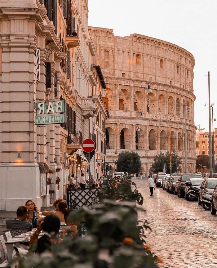 Outdoor dining near historic buildings with the Colosseum in view, illustrating countries that sleep the most concept.