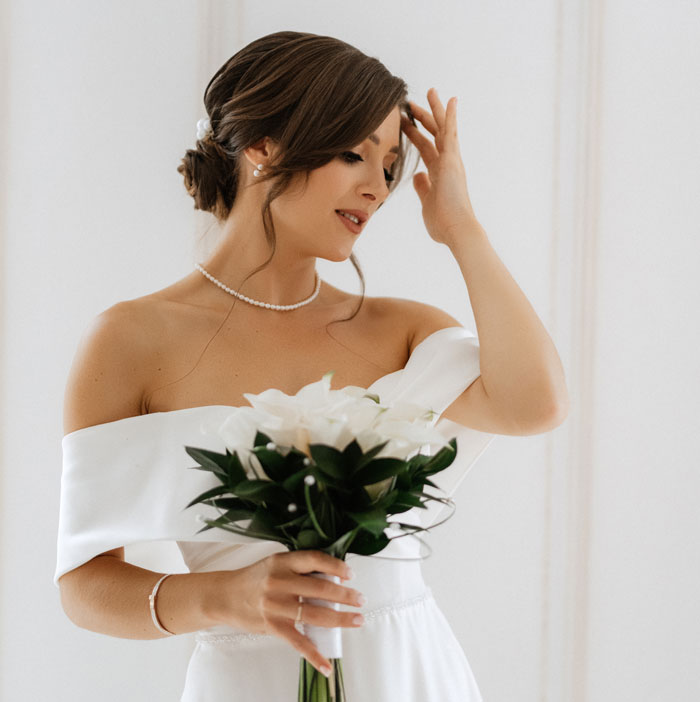 Bride in an elegant white dress holding a bouquet, portraying a bridezilla moment before a family meeting unfolds.