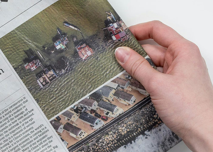 Person holding a newspaper featuring aerial images, illustrating wacky stories shared by people hoping to be believed.