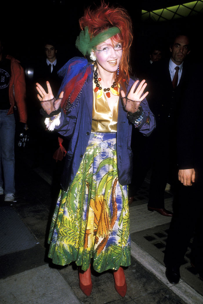 Woman in a vibrant, eclectic outfit with red hair and colorful skirt showcasing wild Grammys looks.