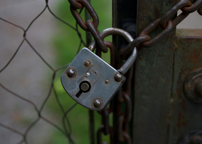 Old rusty padlock securing a chain on a metal gate, representing wacky stories locked away and wanting belief.