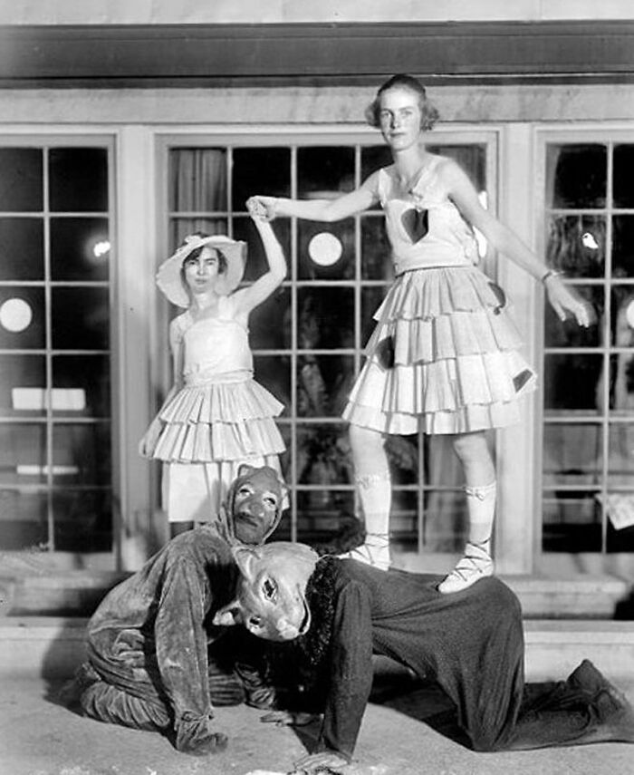 Old black and white photo of people in strange costumes posing in an odd and creepy vintage setting.