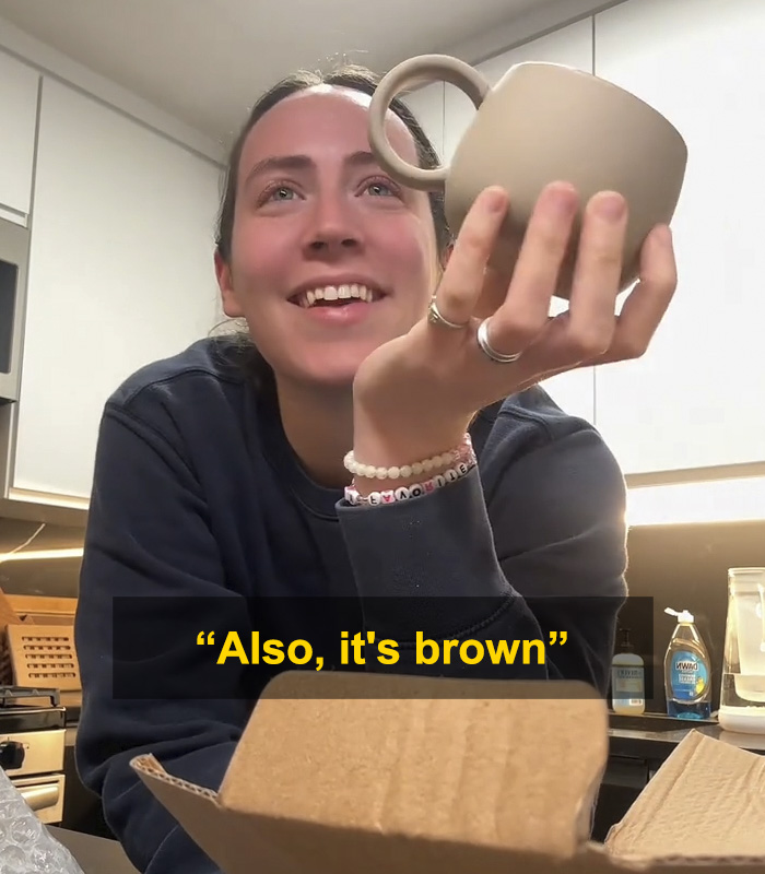 Woman holding up a brown mug gift from fiancé, sparking a huge relationship debate online about the present. Woman holding up a brown mug gift from fiancé, sparking a huge relationship debate online about the present.