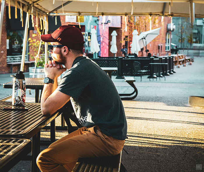 Man sits alone at outdoor table, reflecting deeply, symbolizing emotional investment in a random family group chat.
