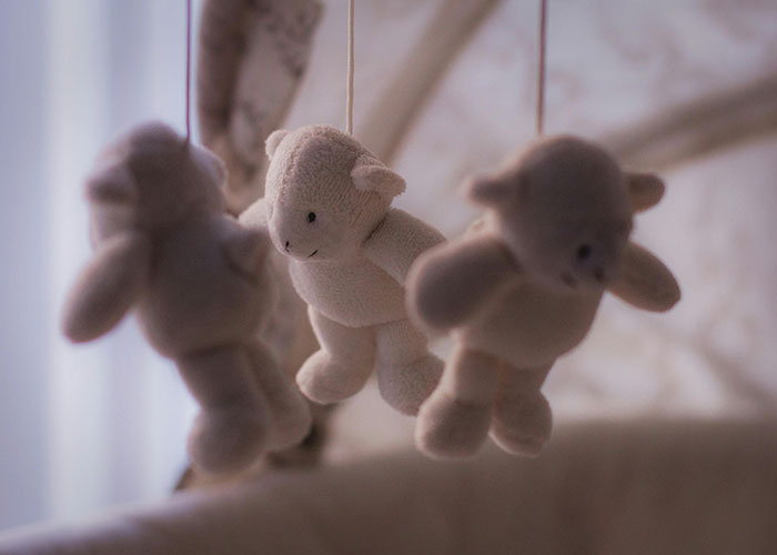 Soft plush baby shower mobile with stuffed animals hanging delicately, symbolizing a rejected inappropriate baby shower idea.