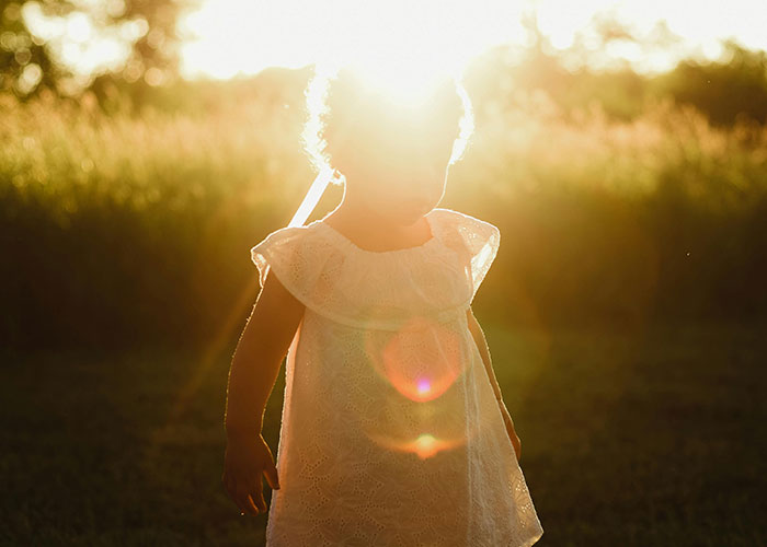 Young child standing in sunlight outdoors, symbolizing experiences of men facing changes after learning they were not the biological parent.
