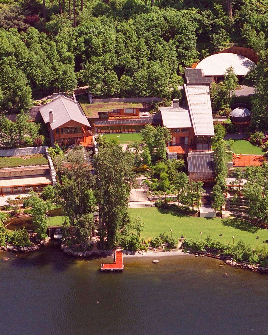 Aerial view of ultra-rich celebrity houses surrounded by lush greenery and situated along a waterfront with private docks.