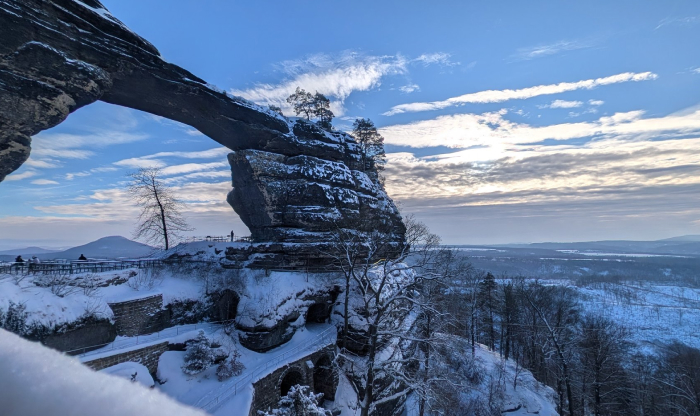 Snow-covered natural rock arch in a scenic winter landscape, one of the forbidden places on Earth rarely visited.