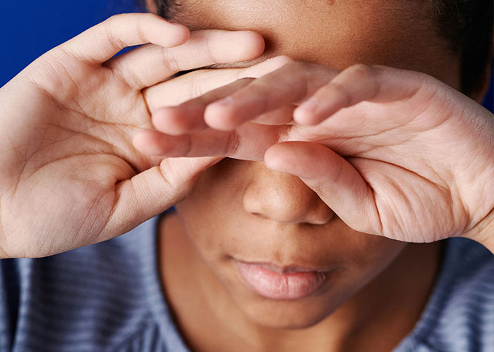 Close-up of a child covering their eyes with hands, illustrating kids with no filter revealing family lore.