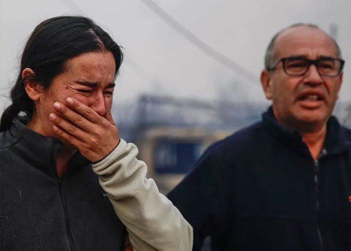Woman covering her face in distress and man speaking, amid the chaos after Chile wildfires burned the town overnight. Woman covering her face in distress and man speaking, amid the chaos after Chile wildfires burned the town overnight.